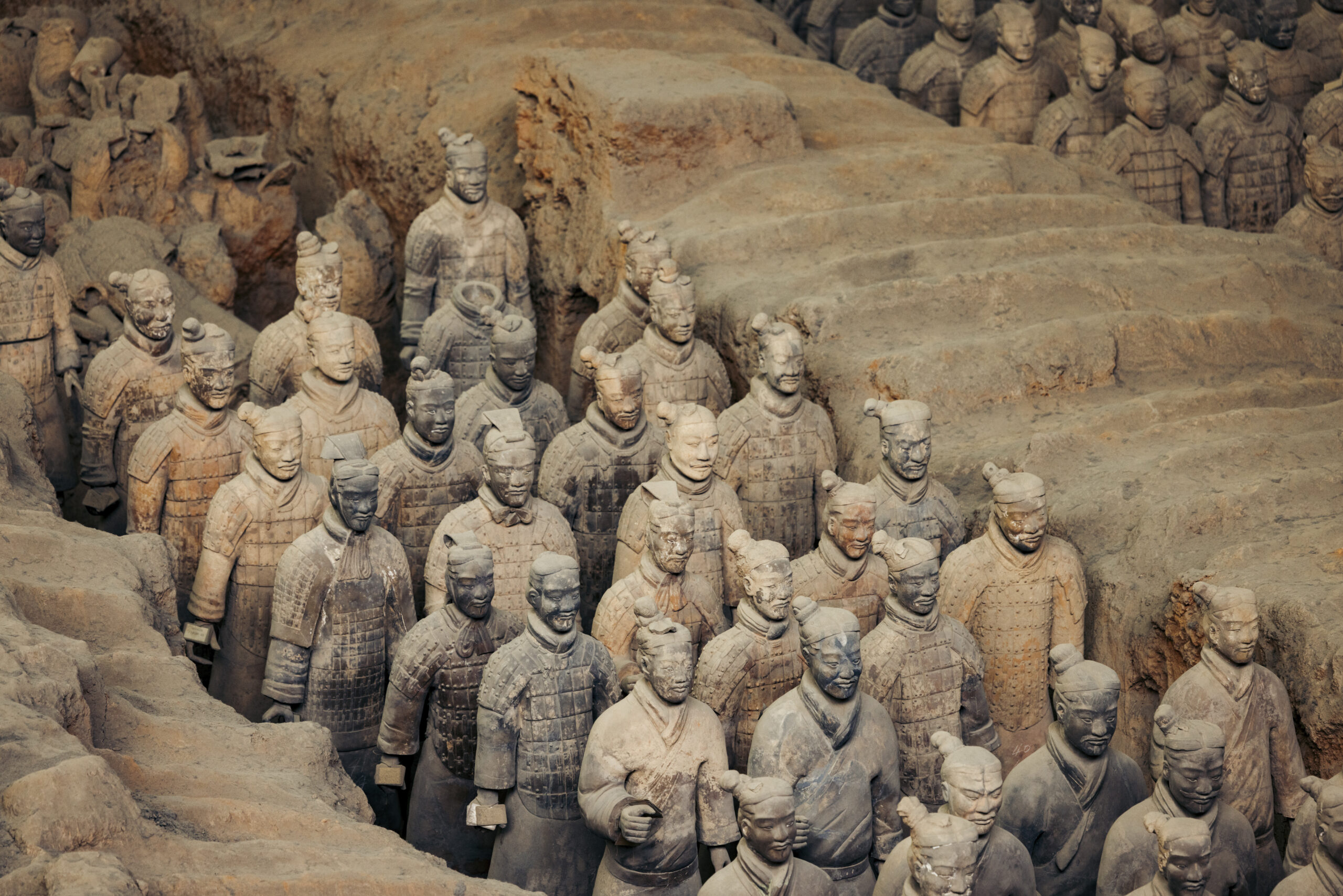 Fileiras de Guerreiros de Terracota com armaduras e penteados detalhados, em um fosso de escavação em Xi’an.
