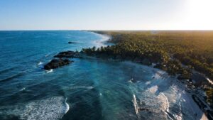 Vista aérea da praia de Tulum, no Caribe mexicano, com mar turquesa, faixa de areia branca e hotéis boutique entre a vegetação