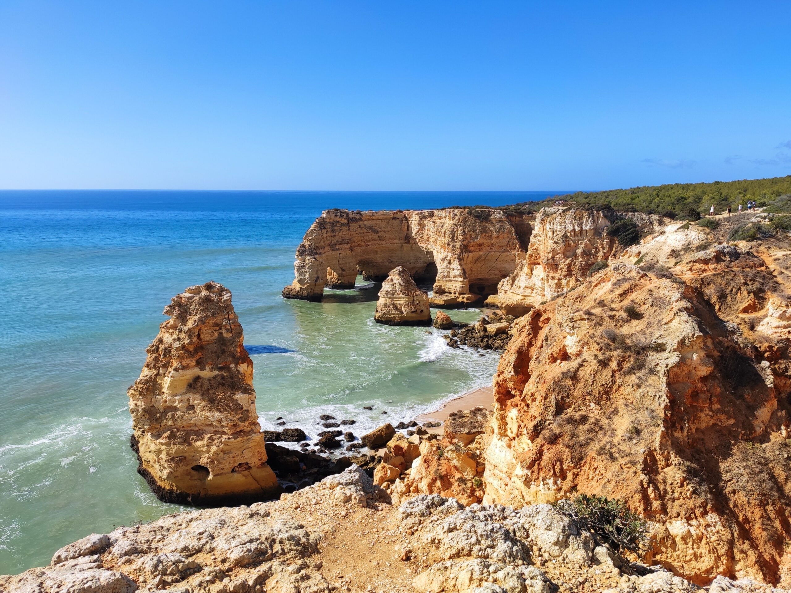 Falésias douradas e arcos naturais na Praia da Marinha, no Algarve, com águas em tons de turquesa e verde-esmeralda
