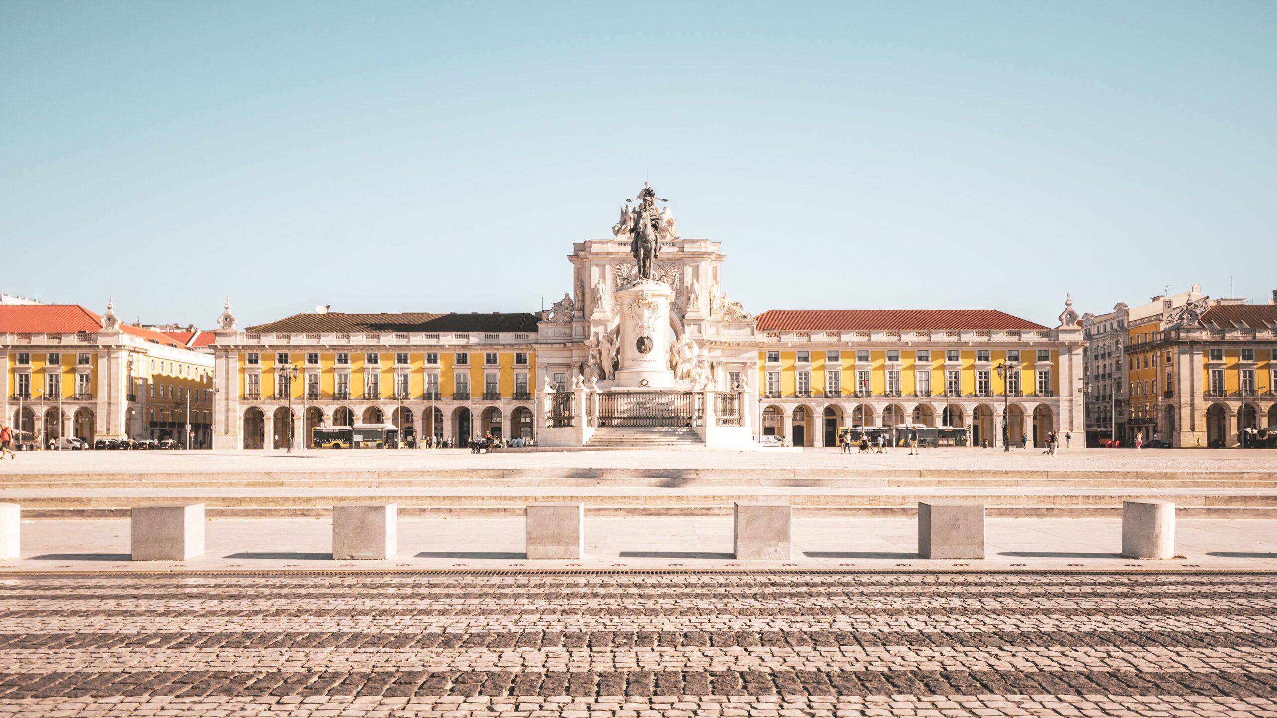 Praça do Comércio em Lisboa com a estátua equestre de Dom José I e o Arco da Rua Augusta ao centro, ladeados pelos edifícios amarelos pombalinos