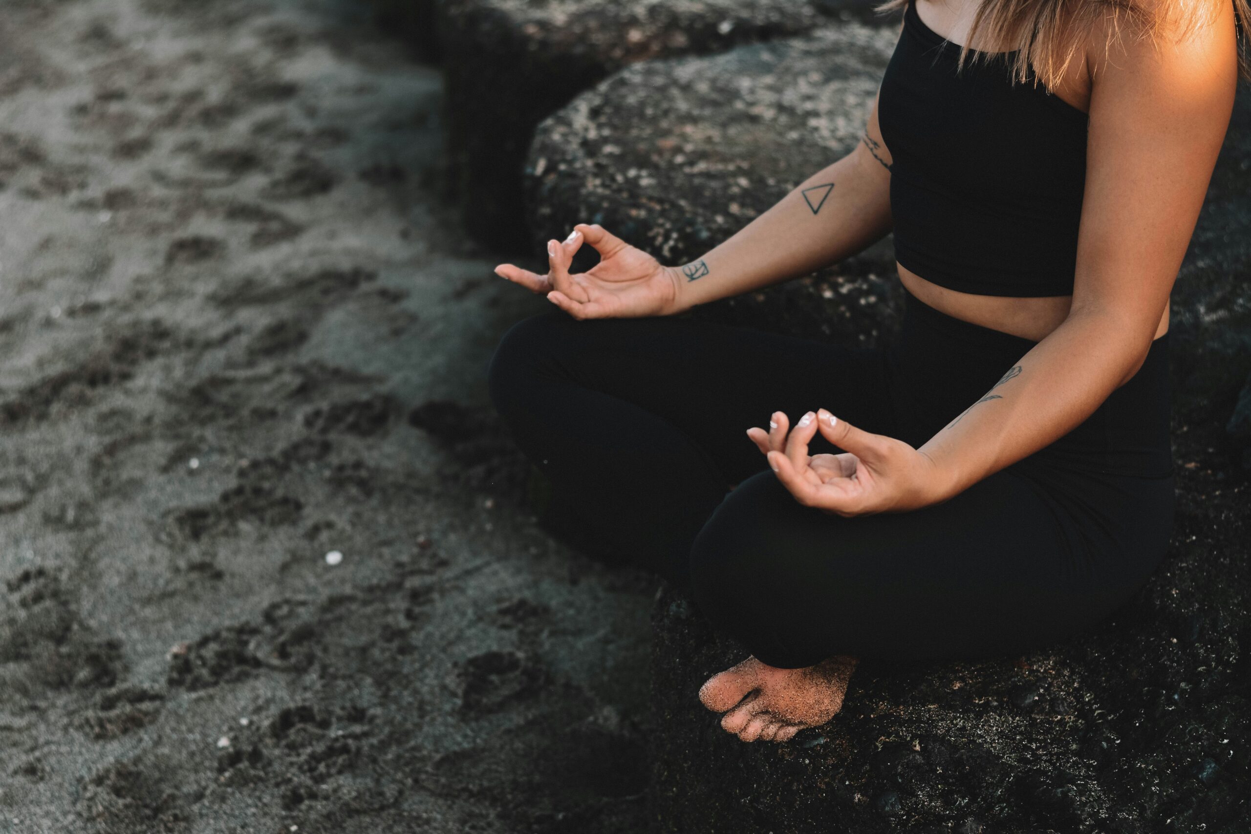 Mulher meditando na praia com mindfulness.