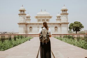 Mulher viajando sozinha com mochila diante de monumento histórico de mármore branco