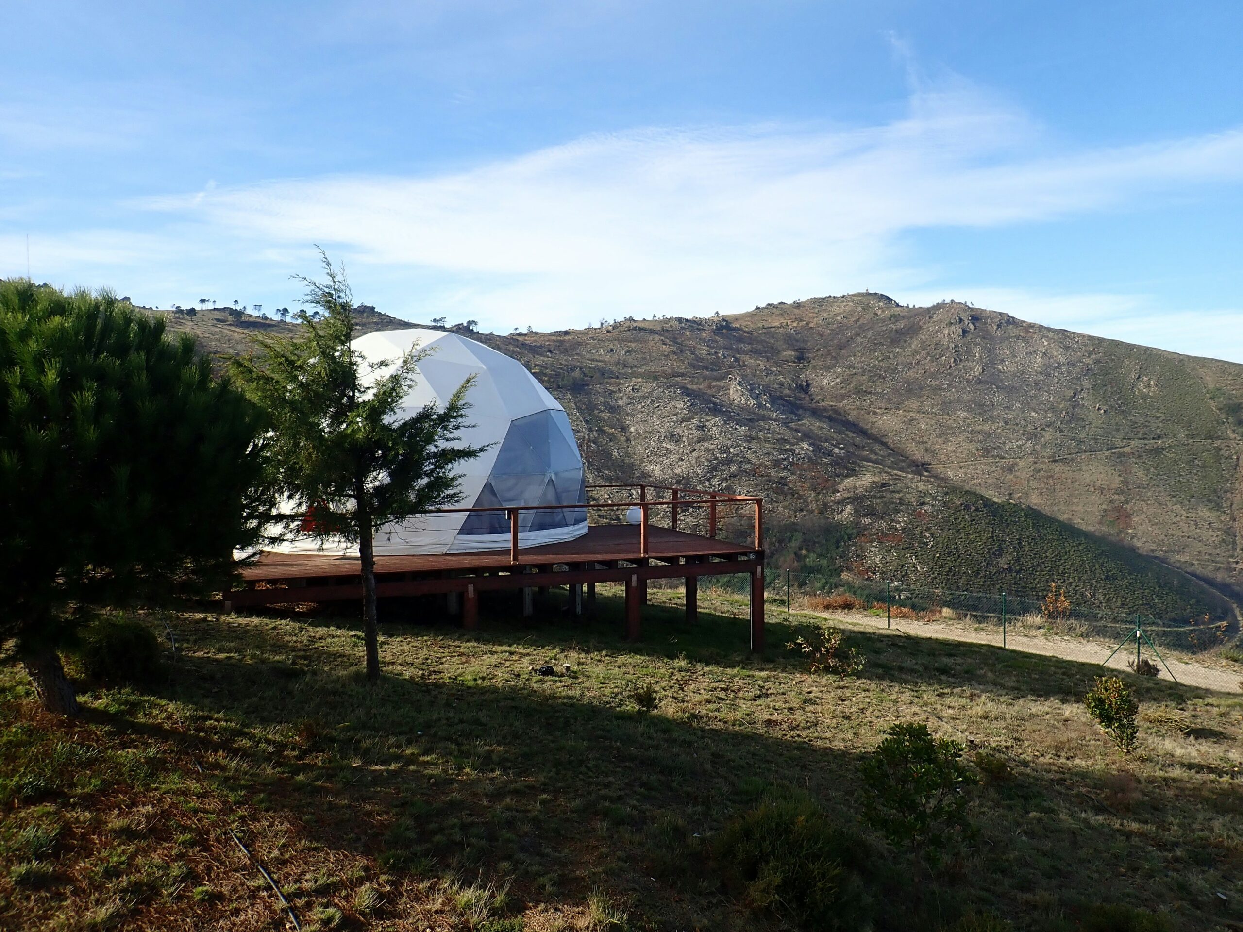 Domo geodésico de glamping sobre deck de madeira elevado com vista para montanhas