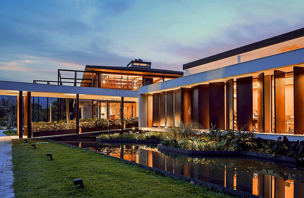 Fachada do Clara Arte ao entardecer, com arquitetura contemporânea e espelho d'água na entrada