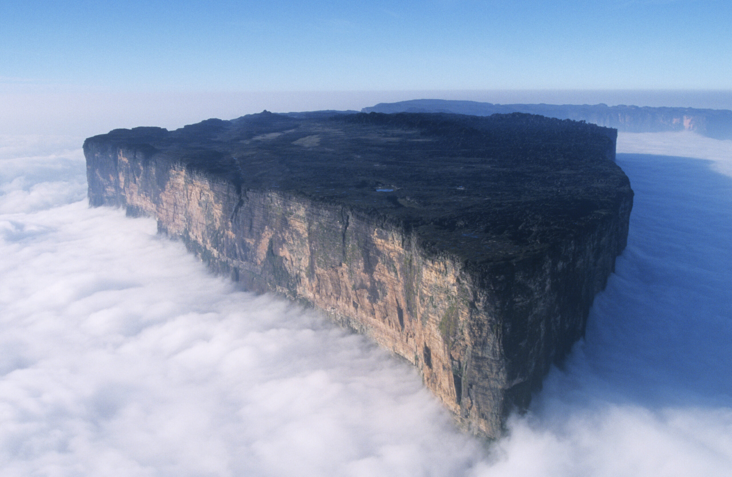 Monte Roraima visto de cima das nuvens, mostrando o platô de paredes verticais na fronteira entre Venezuela, Brasil e Guiana