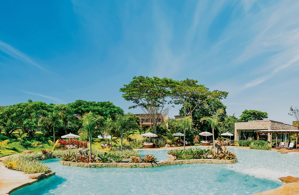 Piscina externa do Clara Dourado cercada por jardins tropicais e áreas de descanso