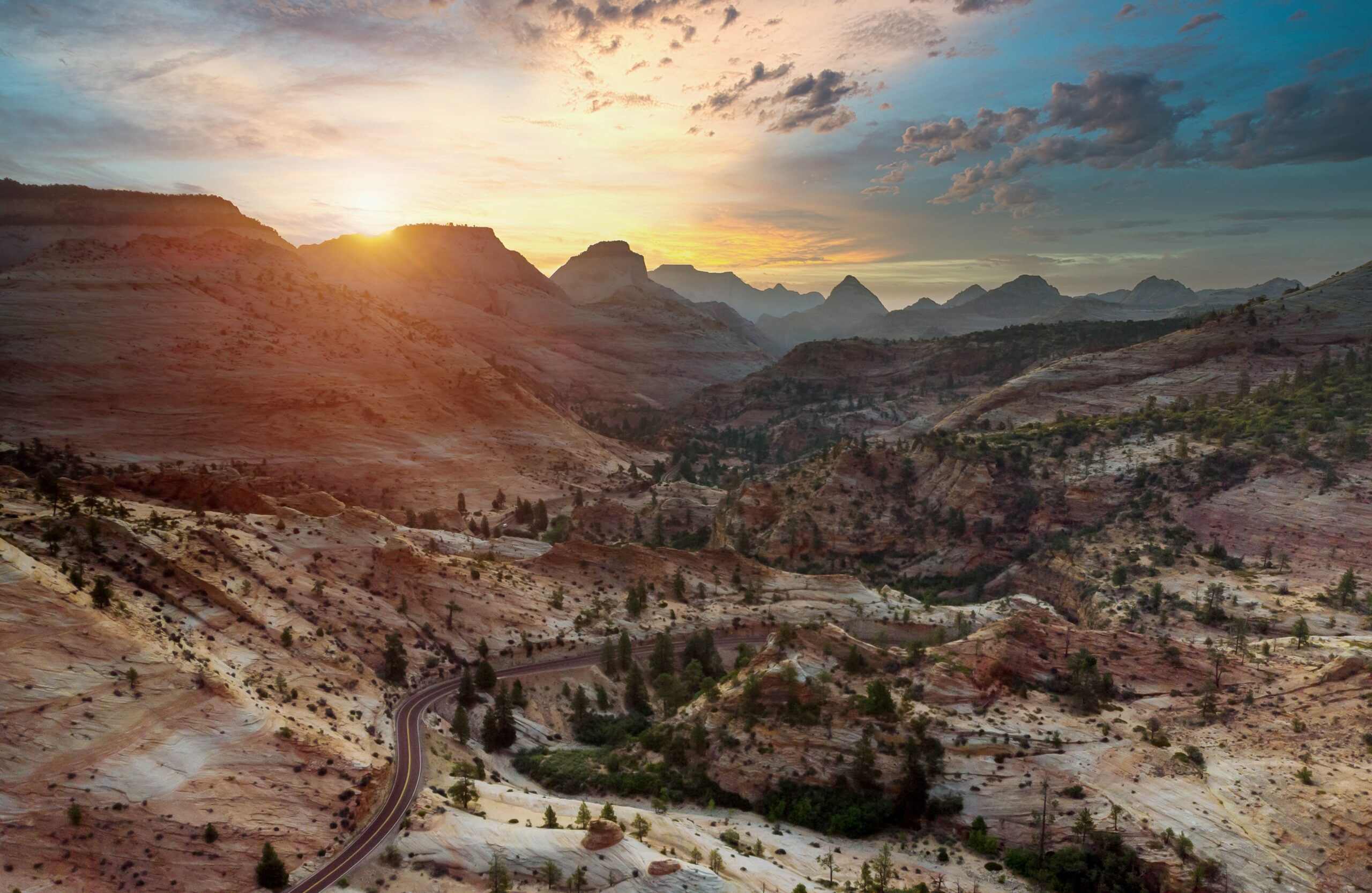 Pôr do sol sobre os desfiladeiros de arenito vermelho do Zion National Park, com a estrada que leva à trilha