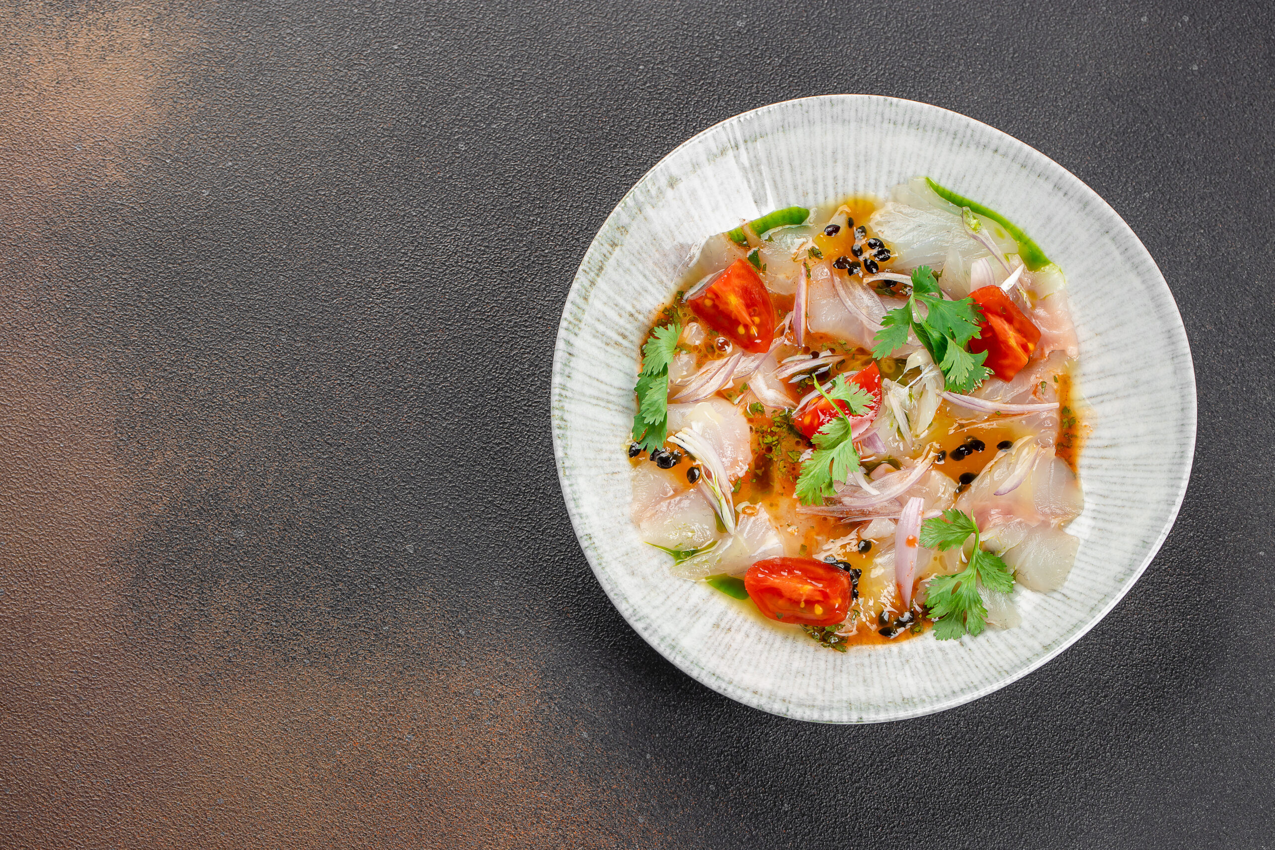 Ceviche contemporâneo de peixe branco com cebola roxa, tomate-cereja, coentro e maracujá, em prato de cerâmica clara.